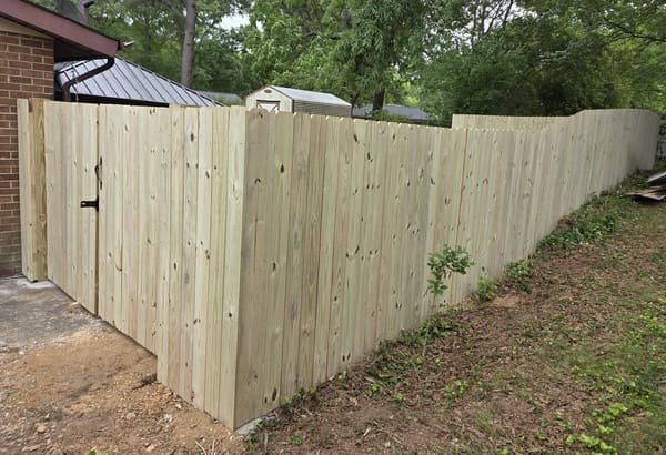 Custom wood privacy fence corner installation connected to house brick exterior in Raleigh NC